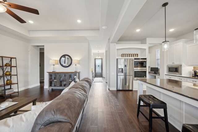 living room featuring a raised ceiling, dark hardwood / wood-style floors, and ceiling fan