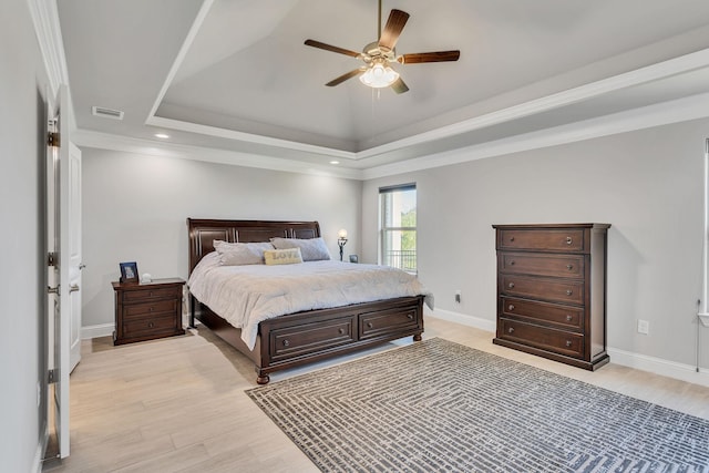 bedroom featuring ceiling fan, ornamental molding, a raised ceiling, and light hardwood / wood-style floors