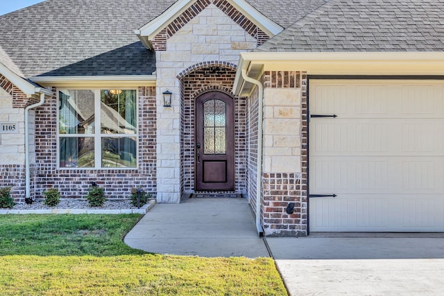 entrance to property with a garage and a lawn