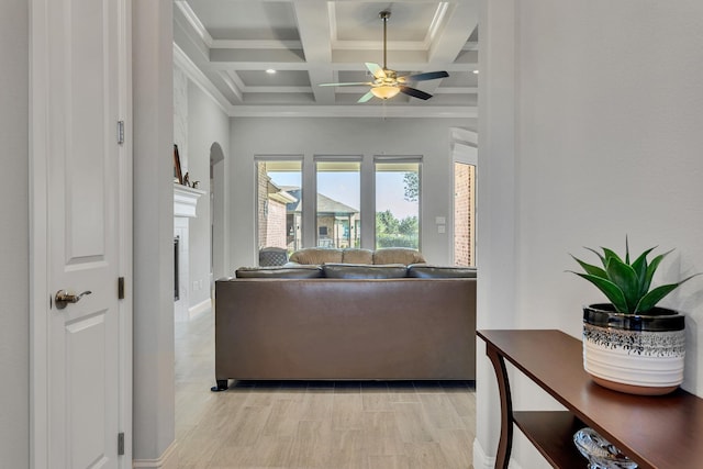 living room with beamed ceiling, crown molding, coffered ceiling, and ceiling fan