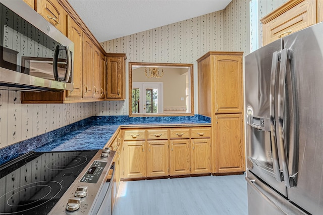 kitchen featuring stainless steel appliances, a textured ceiling, and light wood-type flooring