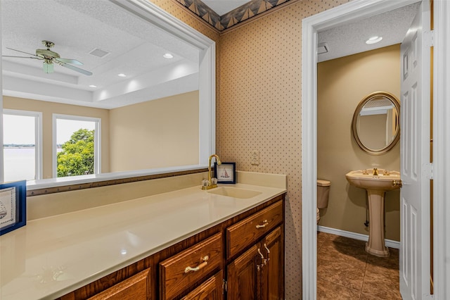 bathroom with tile patterned floors, toilet, sink, a textured ceiling, and a raised ceiling