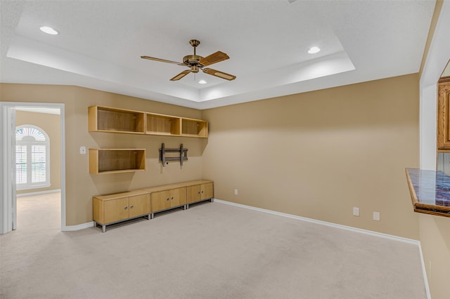 carpeted living room featuring a tray ceiling and ceiling fan