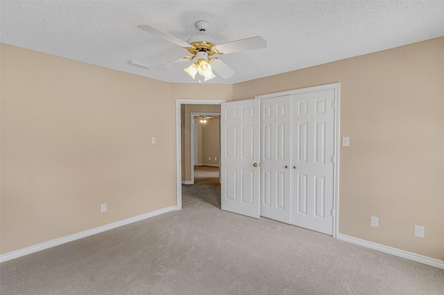 unfurnished bedroom with ceiling fan, light colored carpet, a closet, and a textured ceiling