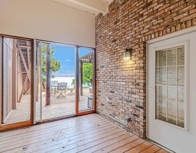 entryway featuring beamed ceiling, brick wall, and hardwood / wood-style flooring