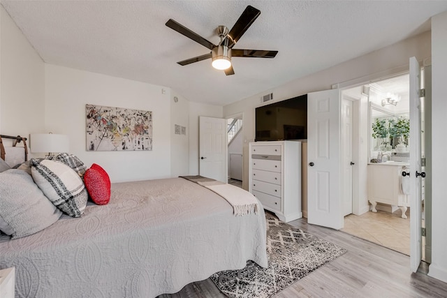 bedroom with ensuite bath, light hardwood / wood-style flooring, a textured ceiling, and ceiling fan