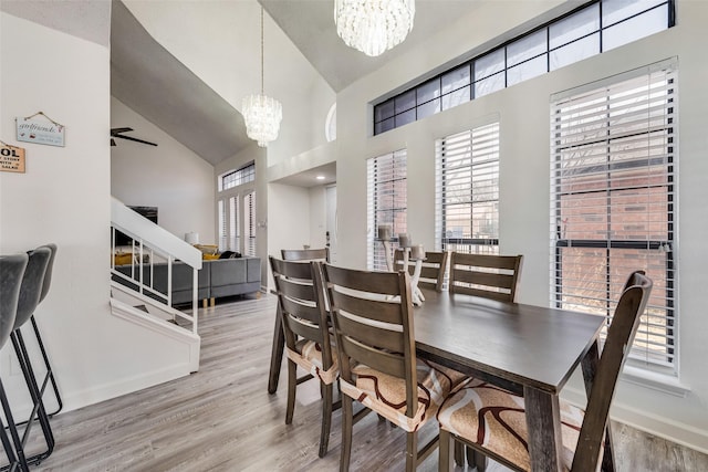 dining room with high vaulted ceiling, a chandelier, and light hardwood / wood-style floors