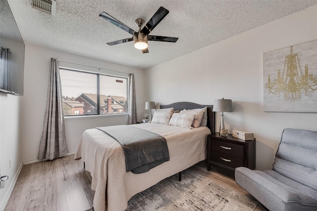 bedroom with light wood-type flooring, a textured ceiling, and ceiling fan