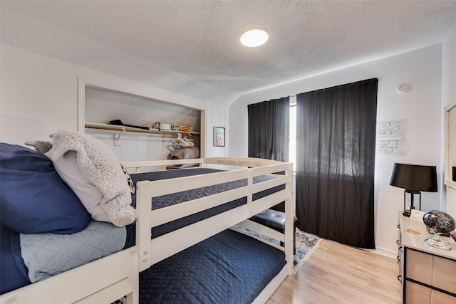 bedroom with hardwood / wood-style flooring, vaulted ceiling, and a textured ceiling