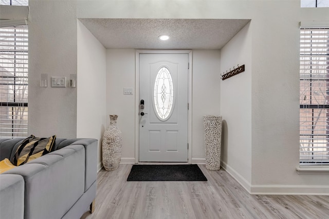 foyer entrance with a textured ceiling and light hardwood / wood-style floors