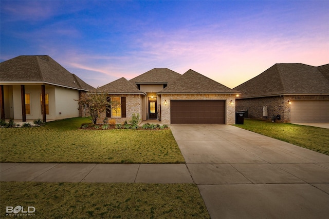 prairie-style house featuring a garage and a yard