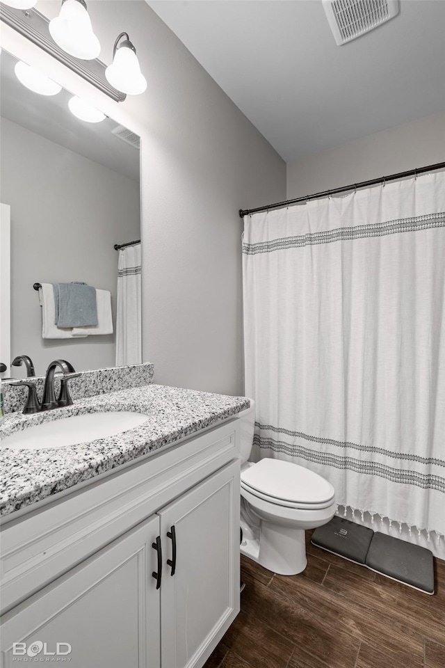 bathroom featuring wood-type flooring, toilet, and vanity