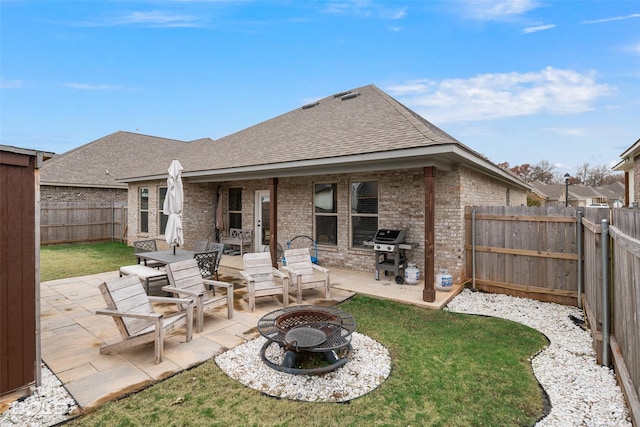 rear view of property with a yard, a patio area, and an outdoor fire pit