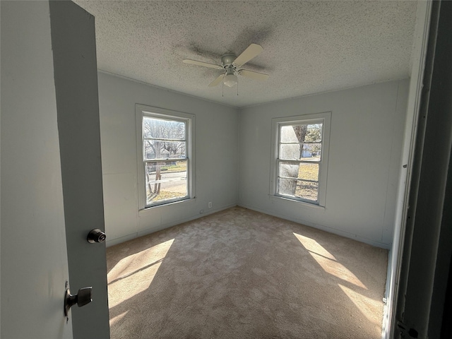 unfurnished room with a healthy amount of sunlight, light colored carpet, and a textured ceiling