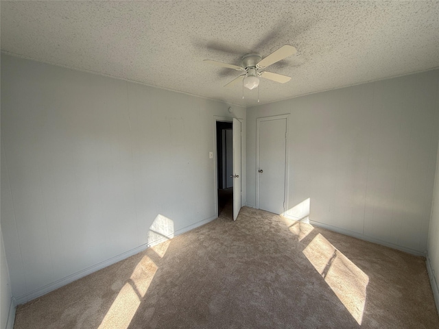 unfurnished room featuring ceiling fan, light colored carpet, and a textured ceiling