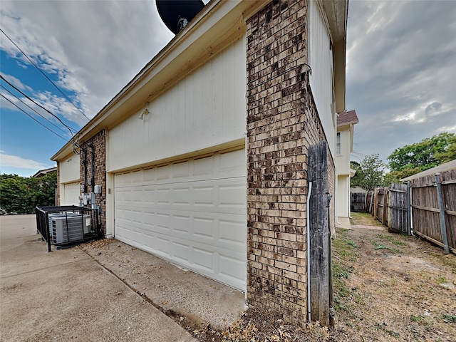 view of property exterior with a garage and central AC unit