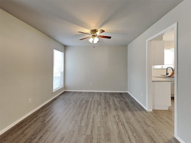 spare room featuring ceiling fan, sink, and light wood-type flooring