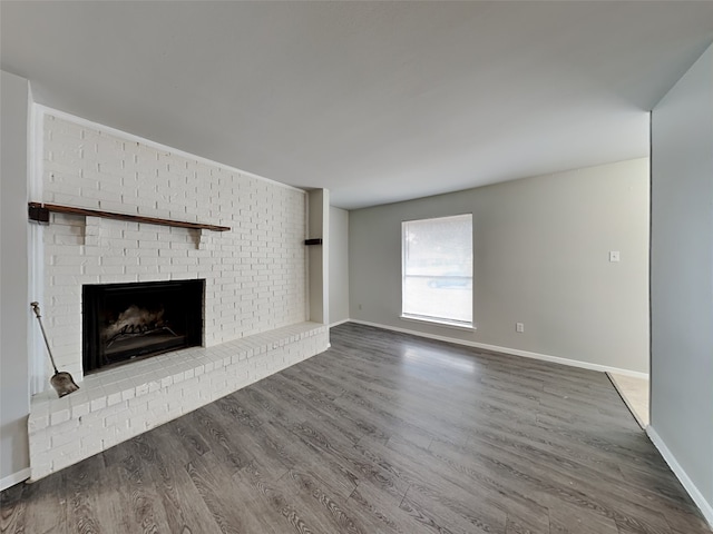 unfurnished living room featuring a brick fireplace and wood-type flooring