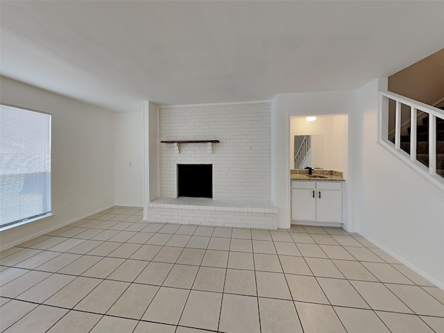 unfurnished living room with a fireplace, sink, and light tile patterned floors