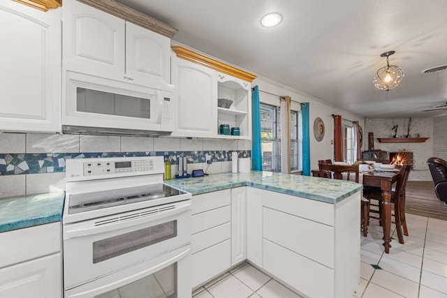 kitchen with decorative light fixtures, kitchen peninsula, white appliances, a fireplace, and white cabinets