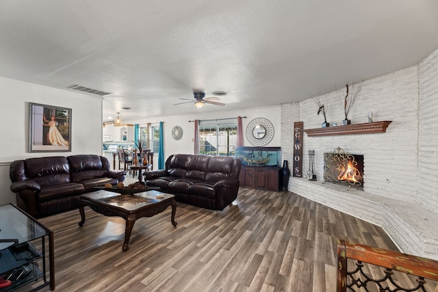 living room with hardwood / wood-style flooring, a fireplace, a textured ceiling, and brick wall