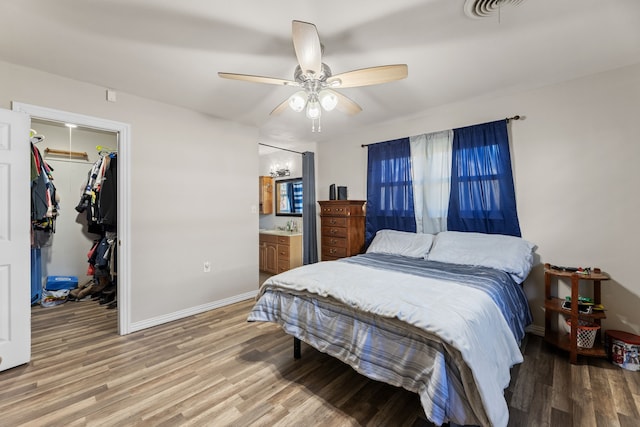 bedroom featuring ensuite bath, a walk in closet, a closet, ceiling fan, and light hardwood / wood-style floors