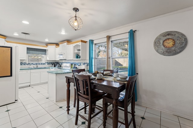 dining area featuring ornamental molding, sink, and light tile patterned floors