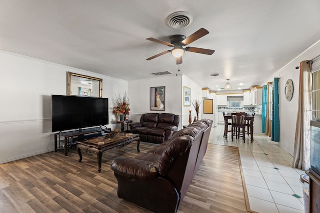 living room featuring crown molding, ceiling fan, and light wood-type flooring