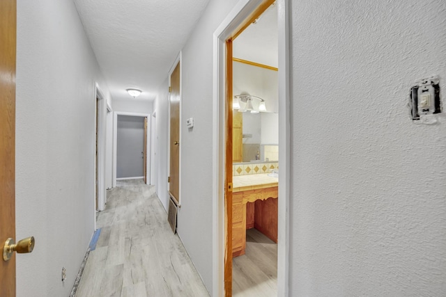 hall with a textured ceiling and light wood-type flooring