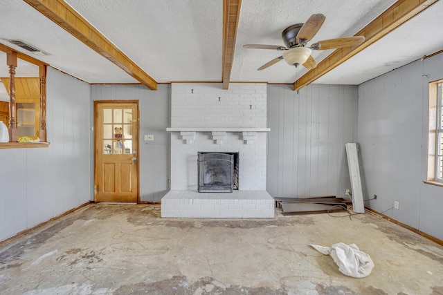 unfurnished living room featuring beamed ceiling, a brick fireplace, a textured ceiling, and wood walls