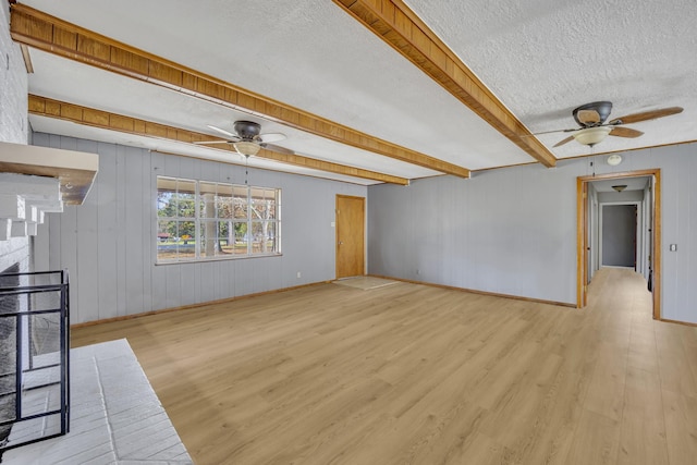 unfurnished living room featuring beam ceiling, light hardwood / wood-style floors, ceiling fan, and a textured ceiling