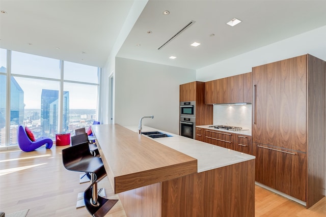 kitchen with a healthy amount of sunlight, appliances with stainless steel finishes, sink, and a center island with sink