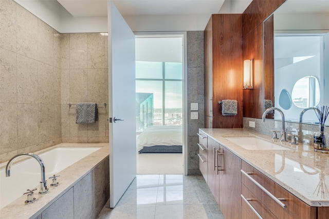 bathroom with tiled tub, vanity, and tile walls