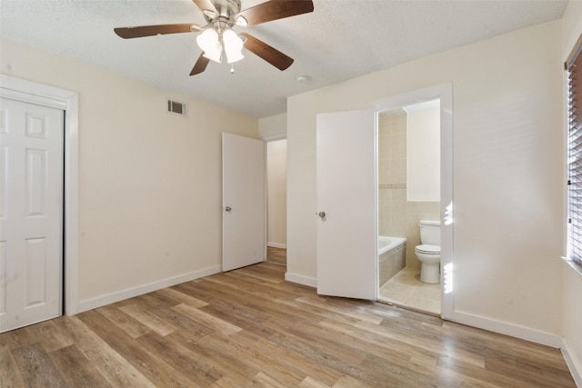 unfurnished bedroom with connected bathroom, a textured ceiling, ceiling fan, and light hardwood / wood-style flooring