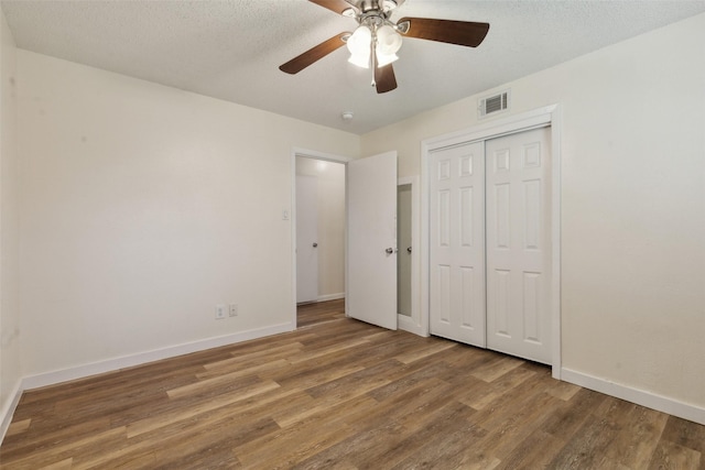 unfurnished bedroom with hardwood / wood-style floors, a textured ceiling, ceiling fan, and a closet