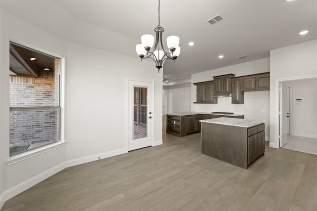 kitchen with pendant lighting, light hardwood / wood-style flooring, dark brown cabinetry, and a center island