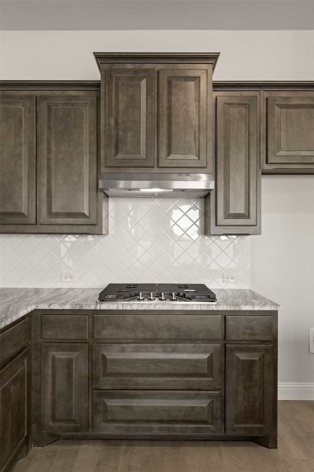 kitchen featuring dark brown cabinets, extractor fan, dark hardwood / wood-style flooring, decorative backsplash, and stainless steel gas stovetop