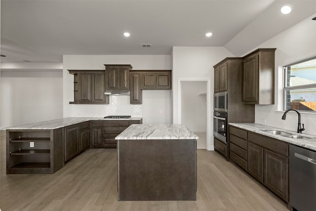 kitchen featuring sink, decorative backsplash, a center island, dark brown cabinetry, and stainless steel appliances