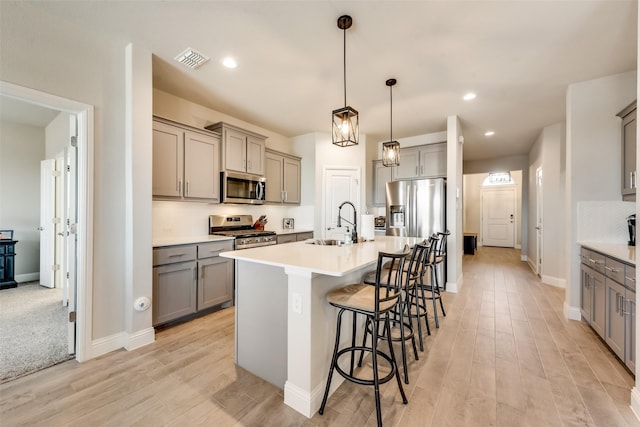 kitchen with sink, decorative light fixtures, a kitchen breakfast bar, an island with sink, and stainless steel appliances