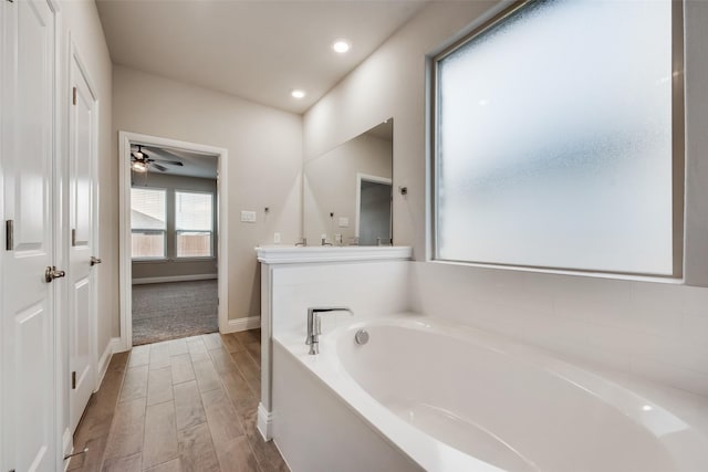 bathroom with vanity, a tub, and ceiling fan