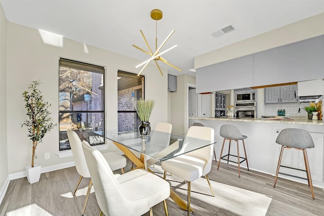 dining space featuring an inviting chandelier and light hardwood / wood-style floors