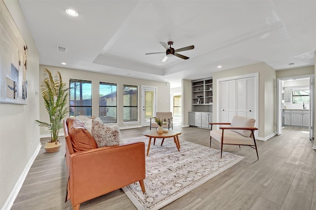 living room with a raised ceiling, plenty of natural light, hardwood / wood-style flooring, and built in features