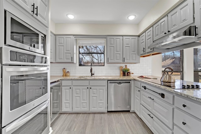 kitchen featuring appliances with stainless steel finishes, sink, light stone counters, and decorative backsplash