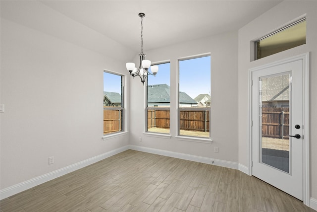 unfurnished dining area with an inviting chandelier, a mountain view, and light hardwood / wood-style floors