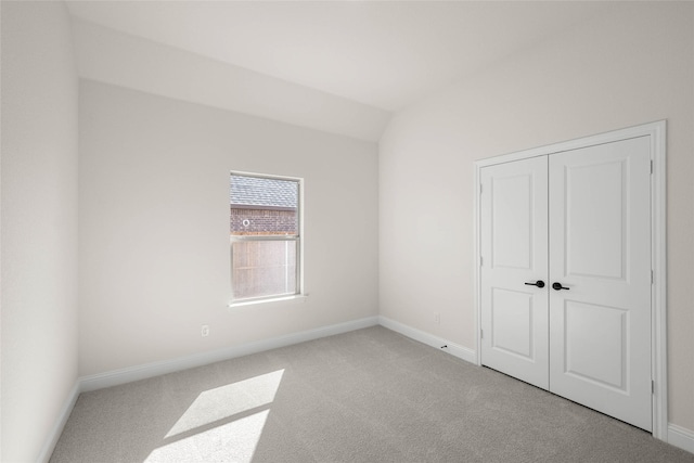 carpeted empty room with lofted ceiling and a closet