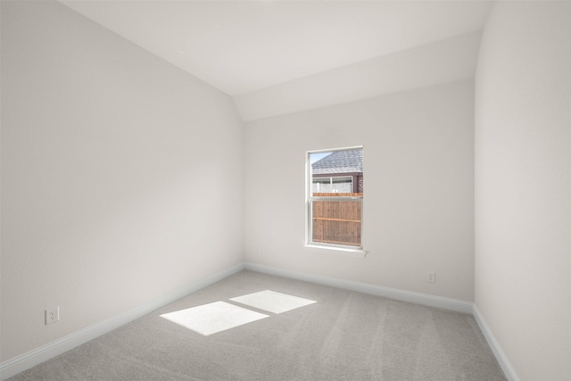 carpeted empty room featuring lofted ceiling