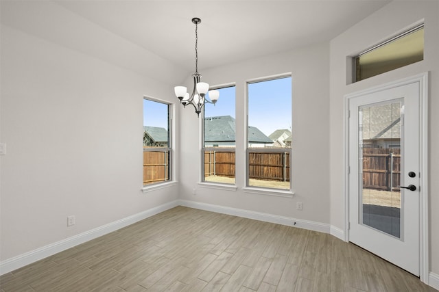 unfurnished dining area featuring a mountain view, a notable chandelier, and light hardwood / wood-style flooring