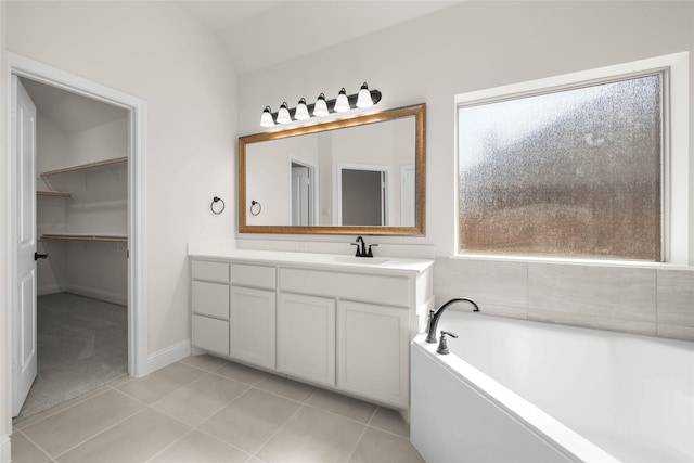 bathroom featuring tile patterned flooring, vanity, a washtub, and lofted ceiling