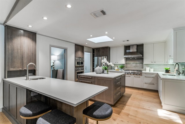 kitchen with a kitchen island, sink, wall chimney range hood, and appliances with stainless steel finishes