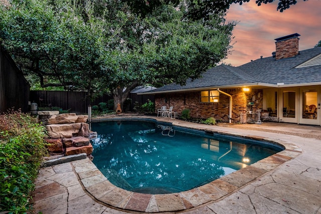 pool at dusk featuring a patio